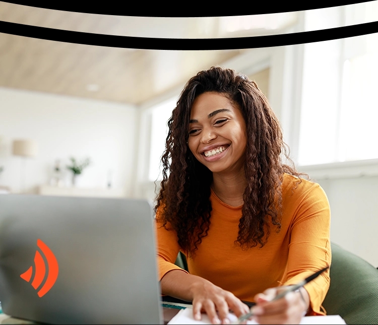 Mulher sorridente, de cabelos cacheados, usando uma blusa laranja enquanto usa um nootbook. Ela faz anotações em um caderno. Há um ícone de wi-fi no canto, parte da identidade visual da Brisanet.