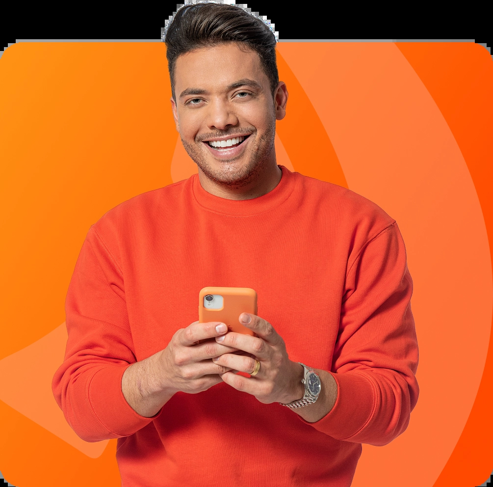 Cantor Wesley Safadão, garoto propaganda da Brisanet, sorrindo com o celular na mão