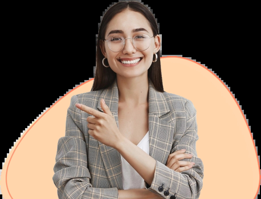 Uma mulher jovem com cabelo longo e liso usa óculos de armação transparente. Ela está vestindo uma jaqueta xadrez cinza sobre uma camiseta branca e jeans. Ela sorri calorosamente e aponta para o canto superior direito com a mão direita, enquanto mantém o braço esquerdo cruzado. Sua expressão é alegre e acolhedora.