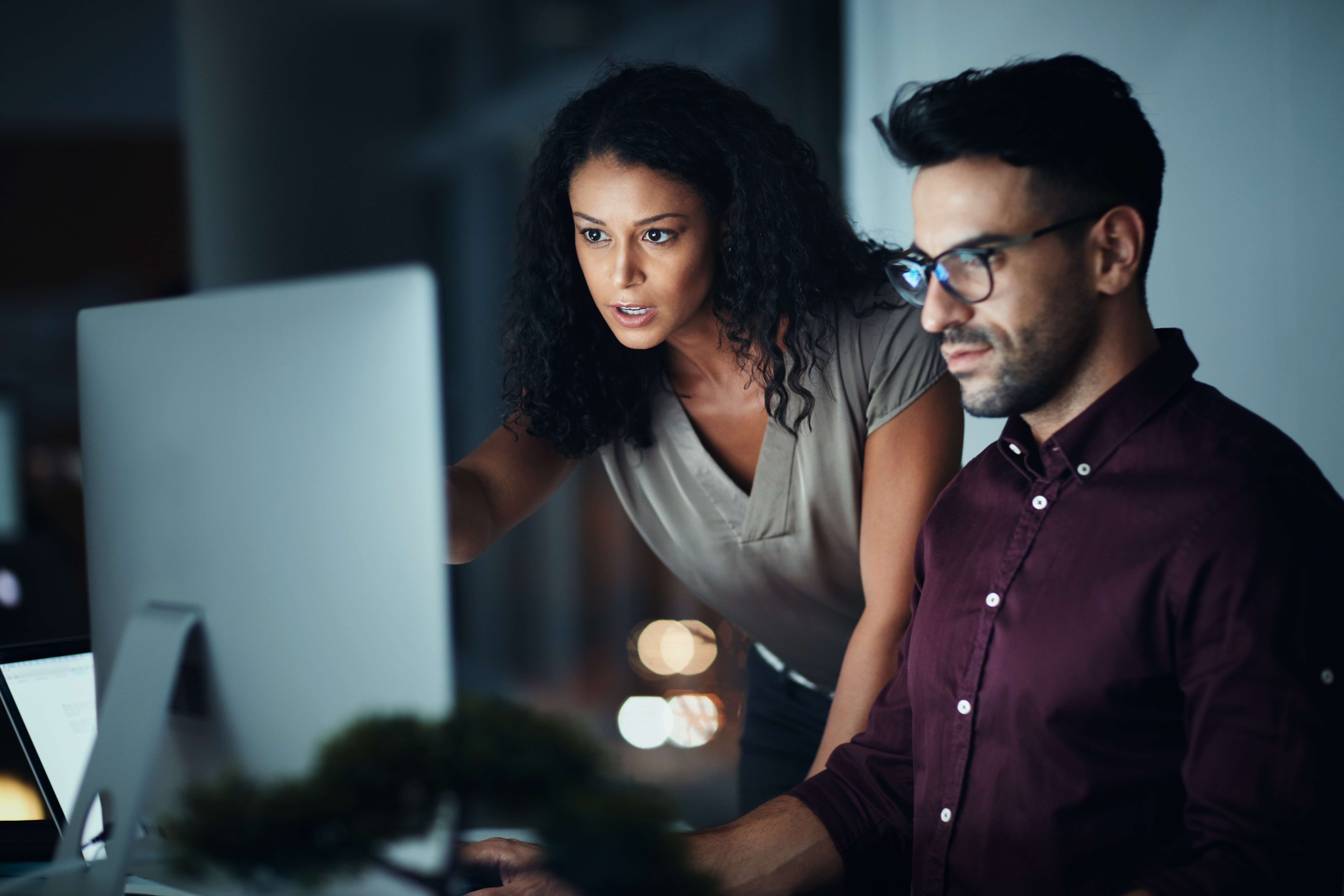 Homem e mulher wm uma empresa enquanto olham para a frente de um computador.